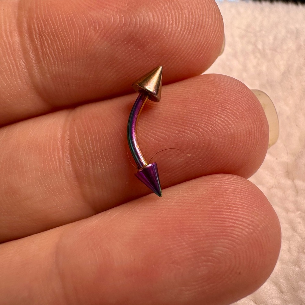 Curved annonized barbell with dual spikes.